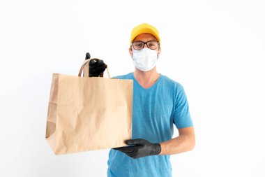 Koruyucu maskeli teslimatçı. Elinde poşet dolusu yiyecek var..