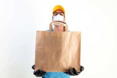 Koruyucu maskeli teslimatçı. Elinde poşet dolusu yiyecek var..