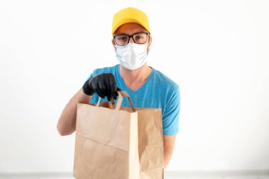Koruyucu maskeli teslimatçı. Elinde poşet dolusu yiyecek var..