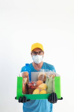 Koruyucu maskeli teslimatçı. Bakkaliye kutusuyla birlikte..