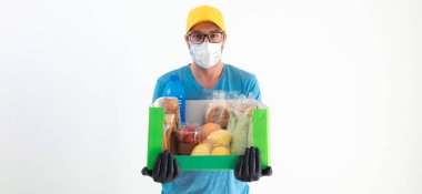 Koruyucu maskeli teslimatçı. Bakkaliye kutusuyla birlikte..