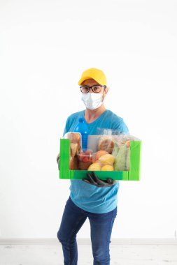 Koruyucu maskeli teslimatçı. Bakkaliye kutusuyla birlikte..