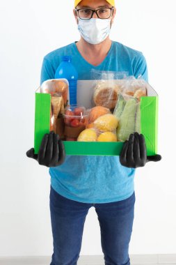 Koruyucu maskeli teslimatçı. Bakkaliye kutusuyla birlikte..