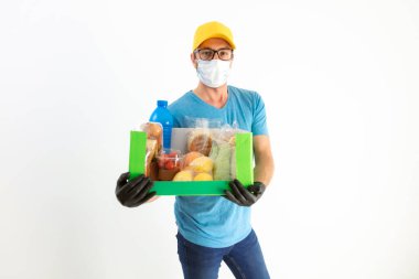 Koruyucu maskeli teslimatçı. Bakkaliye kutusuyla birlikte..