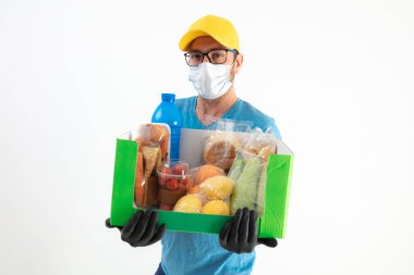 Koruyucu maskeli teslimatçı. Bakkaliye kutusuyla birlikte..