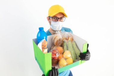Koruyucu maskeli teslimatçı. Bakkaliye kutusuyla birlikte..