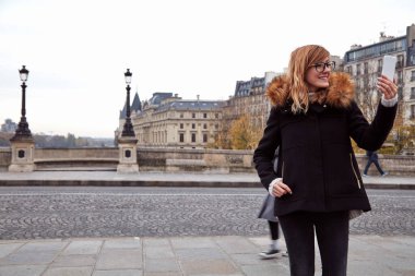 Paris 'in arka planında cep telefonu kullanan bir kız, sonbahar sezonunda Seine nehri..
