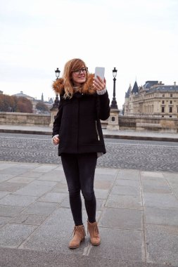 Paris 'in arka planında cep telefonu kullanan bir kız, sonbahar sezonunda Seine nehri..