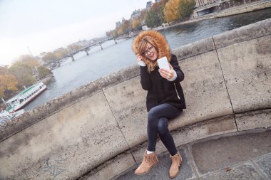 Paris geçmişi olan cep telefonu kullanan bir kız, Seine nehri ve Eyfel kulesi..