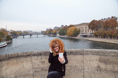 Paris geçmişi olan cep telefonu kullanan bir kız, Seine nehri ve Eyfel kulesi..