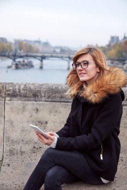 Paris geçmişi olan cep telefonu kullanan bir kız, Seine nehri ve Eyfel kulesi..