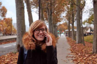 Avrupa 'da sonbahar atmosferli cep telefonu kullanan bir kız.