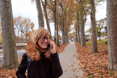 Avrupa 'da sonbahar atmosferli cep telefonu kullanan bir kız.