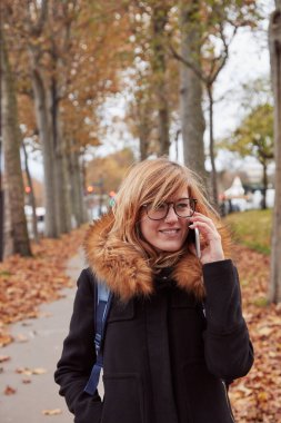 Avrupa 'da sonbahar atmosferli cep telefonu kullanan bir kız.