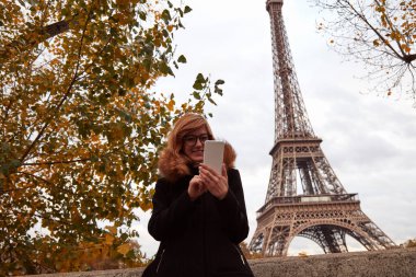 Paris geçmişi olan cep telefonu kullanan bir kız, Seine nehri ve Eyfel kulesi..