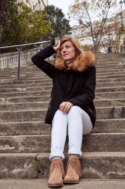 Büyük bir merdivende tek başına oturan tatlı gülen kız..