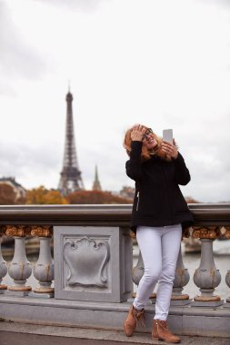 Paris geçmişi olan cep telefonu kullanan bir kız, Seine nehri ve Eyfel kulesi..