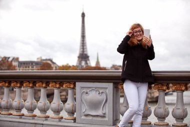 Paris geçmişi olan cep telefonu kullanan bir kız, Seine nehri ve Eyfel kulesi..