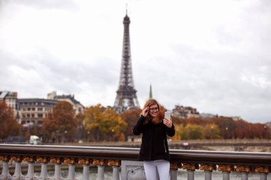 Paris geçmişi olan cep telefonu kullanan bir kız, Seine nehri ve Eyfel kulesi..