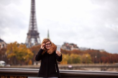 Paris geçmişi olan cep telefonu kullanan bir kız, Seine nehri ve Eyfel kulesi..