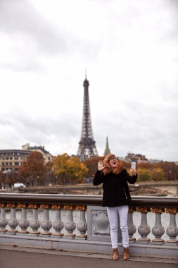 Paris geçmişi olan cep telefonu kullanan bir kız, Seine nehri ve Eyfel kulesi..