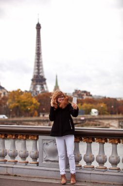 Paris geçmişi olan cep telefonu kullanan bir kız, Seine nehri ve Eyfel kulesi..