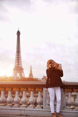 Paris geçmişi olan cep telefonu kullanan bir kız, Seine nehri ve Eyfel kulesi..