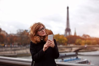 Paris geçmişi olan cep telefonu kullanan bir kız, Seine nehri ve Eyfel kulesi..