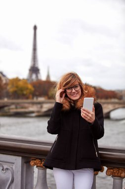 Paris geçmişi olan cep telefonu kullanan bir kız, Seine nehri ve Eyfel kulesi..