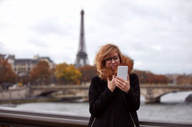 Paris geçmişi olan cep telefonu kullanan bir kız, Seine nehri ve Eyfel kulesi..