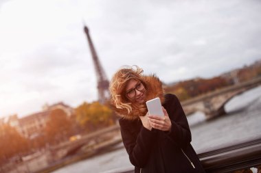 Paris geçmişi olan cep telefonu kullanan bir kız, Seine nehri ve Eyfel kulesi..