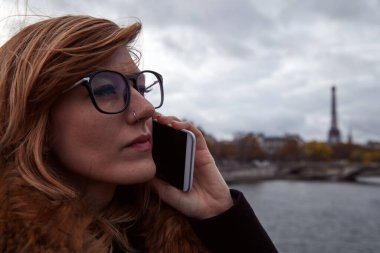 Paris geçmişi olan cep telefonu kullanan bir kız, Seine nehri ve Eyfel kulesi..