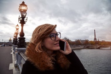 Paris geçmişi olan cep telefonu kullanan bir kız, Seine nehri ve Eyfel kulesi..