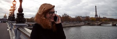 Paris geçmişi olan cep telefonu kullanan bir kız, Seine nehri ve Eyfel kulesi..