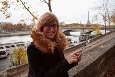 Paris geçmişi olan cep telefonu kullanan bir kız, Seine nehri ve Eyfel kulesi..