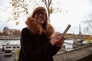 Paris geçmişi olan cep telefonu kullanan bir kız, Seine nehri ve Eyfel kulesi..