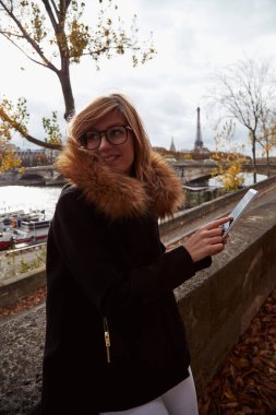 Paris geçmişi olan cep telefonu kullanan bir kız, Seine nehri ve Eyfel kulesi..