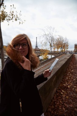 Paris geçmişi olan cep telefonu kullanan bir kız, Seine nehri ve Eyfel kulesi..