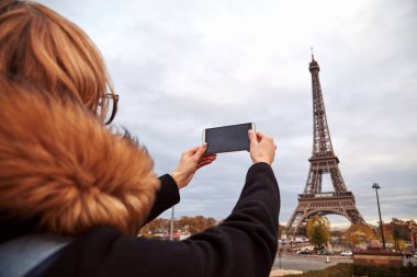 Paris geçmişi ve Eyfel kulesi olan cep telefonu kullanan bir kız..