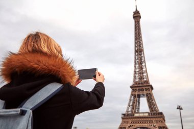 Paris geçmişi ve Eyfel kulesi olan cep telefonu kullanan bir kız..