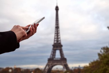 Paris geçmişi ve Eyfel kulesi olan cep telefonu kullanan bir kız..