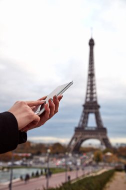 Paris geçmişi ve Eyfel kulesi olan cep telefonu kullanan bir kız..