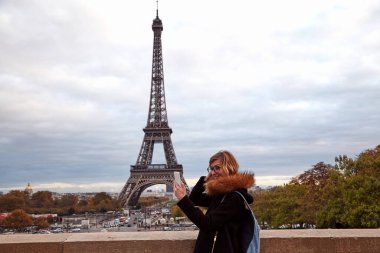 Paris geçmişi ve Eyfel kulesi olan cep telefonu kullanan bir kız..