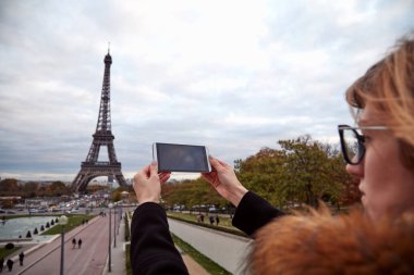 Paris geçmişi ve Eyfel kulesi olan cep telefonu kullanan bir kız..