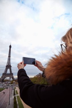 Paris geçmişi ve Eyfel kulesi olan cep telefonu kullanan bir kız..