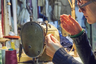 Evde retro dikiş makinesi kullanan bir kadın terzi, hobi konsepti..