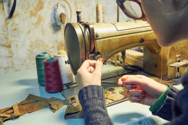 Evde retro dikiş makinesi kullanan bir kadın terzi, hobi konsepti..