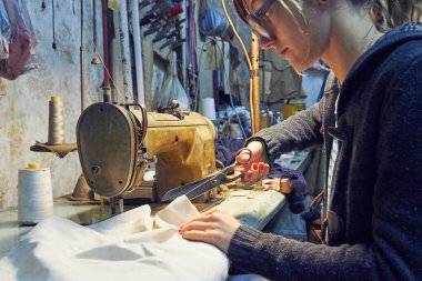 Evde retro dikiş makinesi kullanan bir kadın terzi, hobi konsepti..