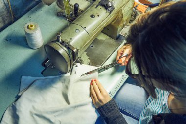 Evde retro dikiş makinesi kullanan bir kadın terzi, hobi konsepti..