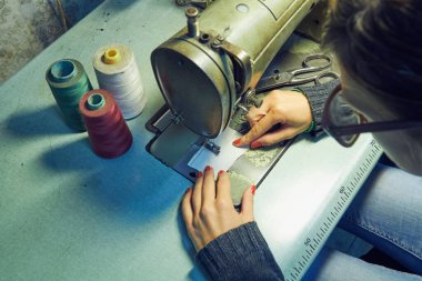 Evde retro dikiş makinesi kullanan bir kadın terzi, hobi konsepti..